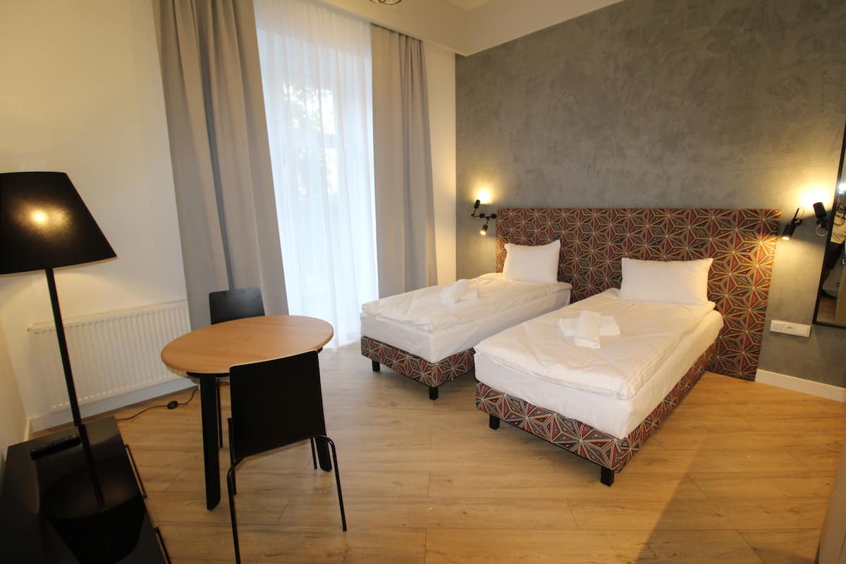 A hotel room with two beds, a table, and a chair.