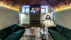 A cozy lounge area with a curved ceiling, a fireplace, and a television mounted on the wall. - Apartamenty Nowa Kamienica (Czestochowa)