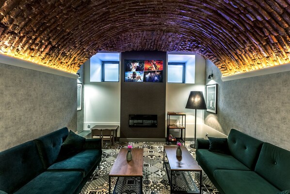 A cozy lounge area with a curved ceiling, a fireplace, and a television mounted on the wall. - Apartamenty Nowa Kamienica (Czestochowa)
