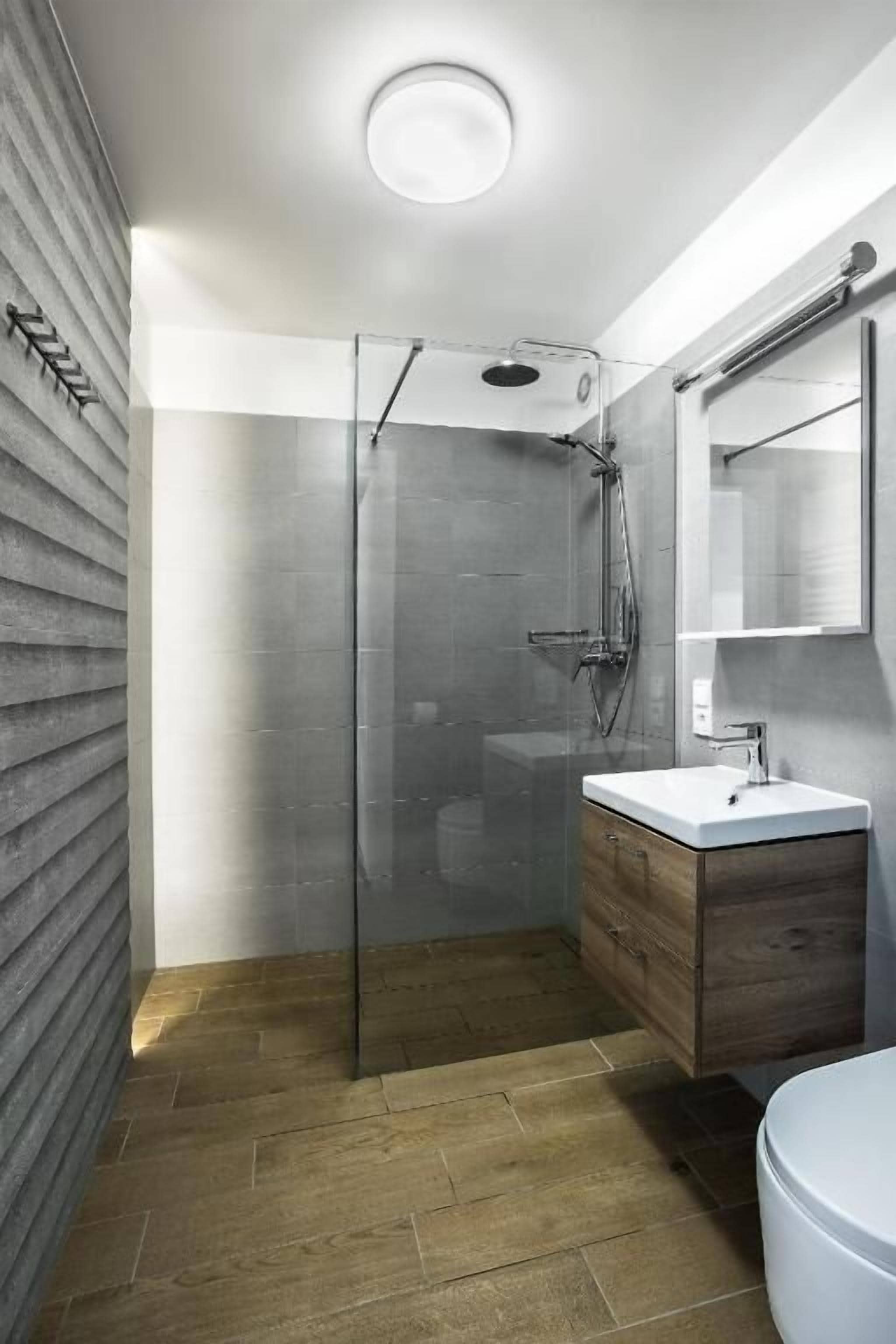 A modern bathroom with a glass-enclosed shower, a wooden vanity, and a large mirror.