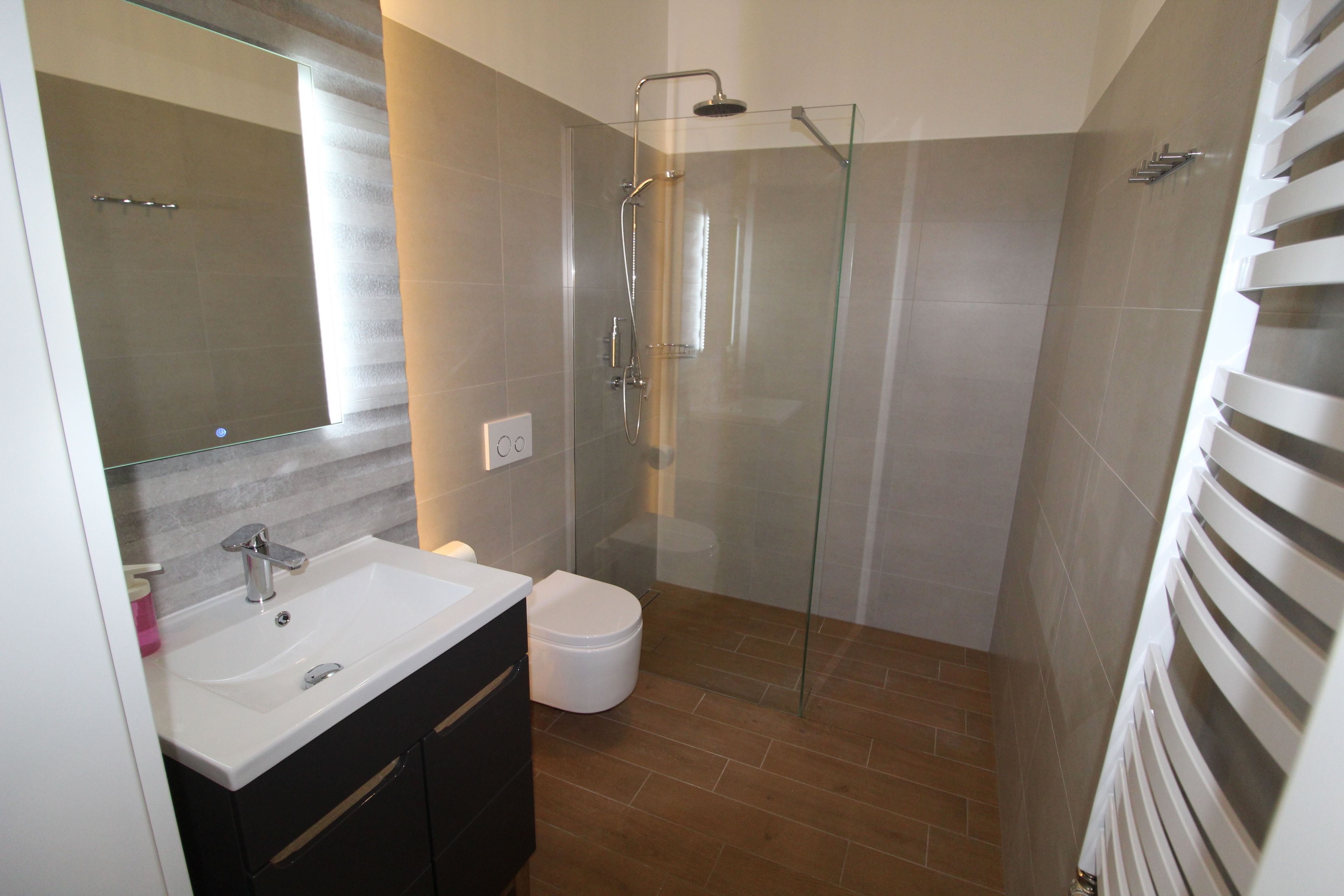 A modern bathroom with a glass-enclosed shower, a white sink with a mirror, and a black vanity.