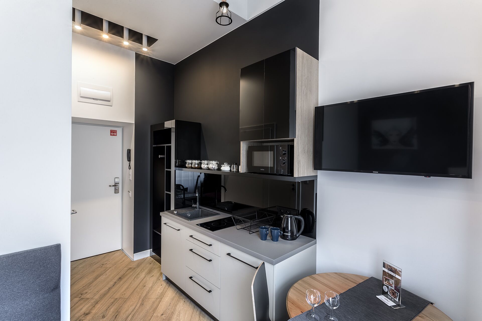 A modern kitchen with a built-in microwave, stove, and a flat-screen TV mounted on the wall.