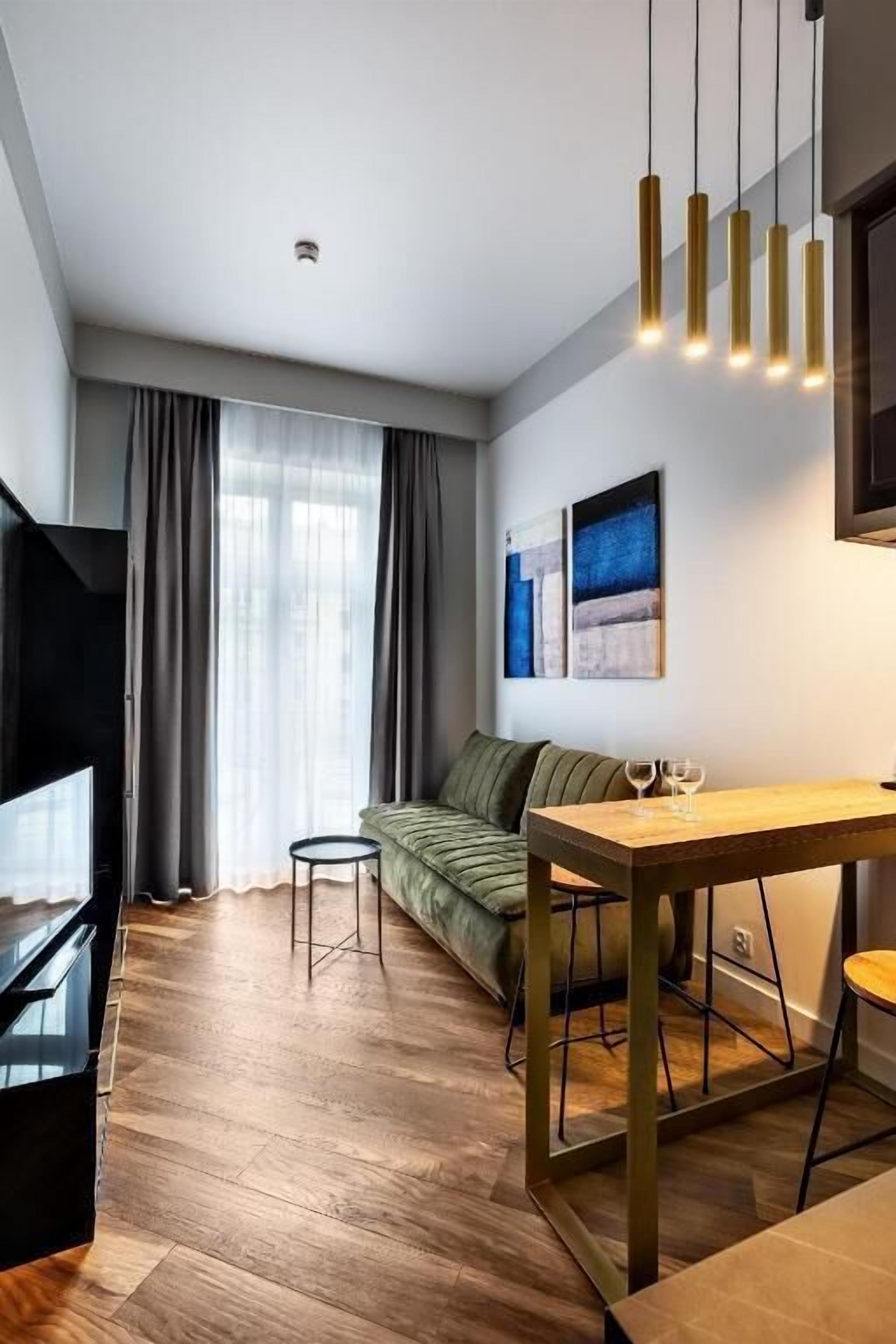 A modern living room with a sofa, a wooden dining table, and a television.