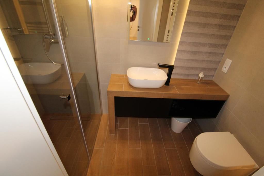 A modern bathroom with a glass-enclosed shower, a white sink, and a toilet.