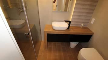 A modern bathroom with a glass-enclosed shower, a white sink, and a toilet.