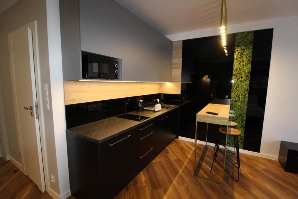 A modern kitchen with dark cabinetry, a microwave, and a wooden countertop.