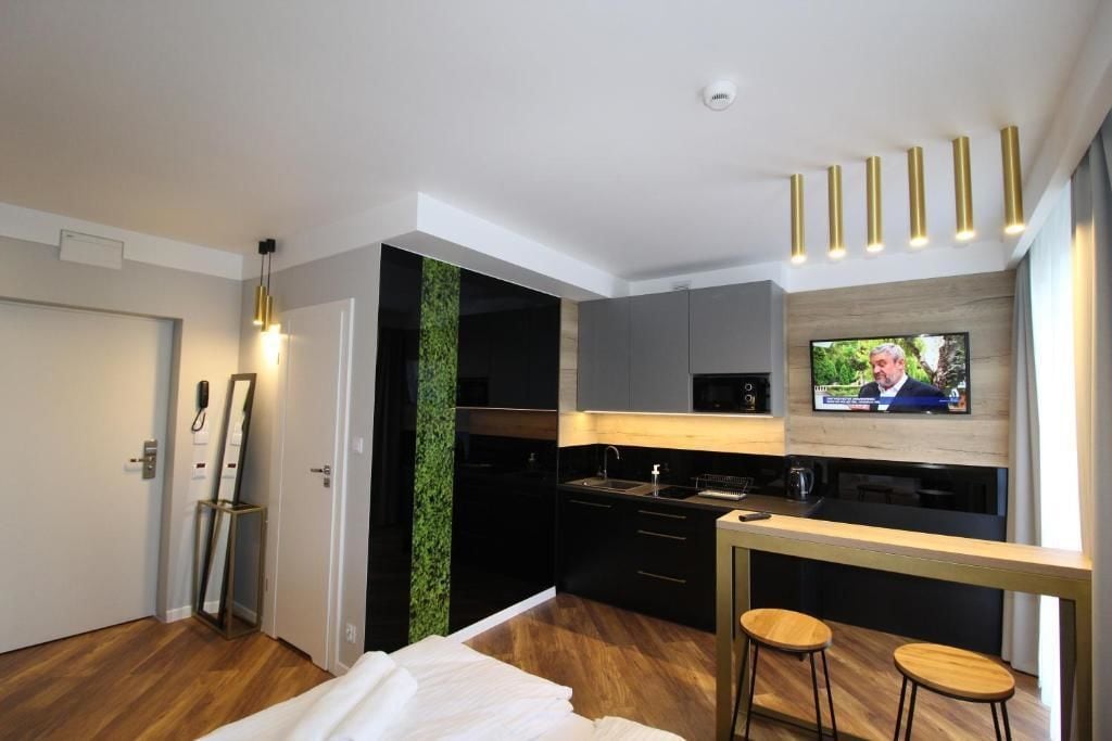 Moderni hotellihuone, jossa on pieni keittiö, sänky, televisio ja baarialue.