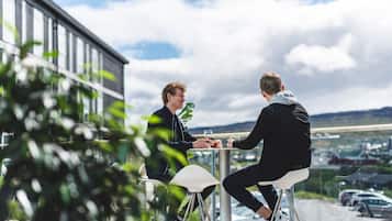 Two people sitting at a table outdoors with a view of a parking lot and buildings in the background.