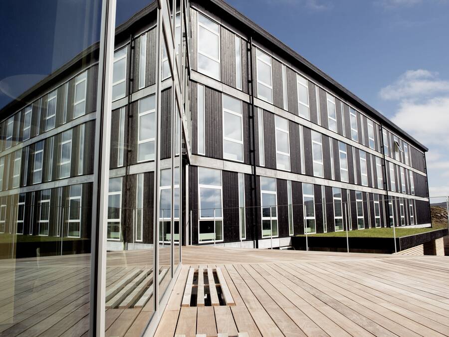 A modern building with large windows and a wooden deck.