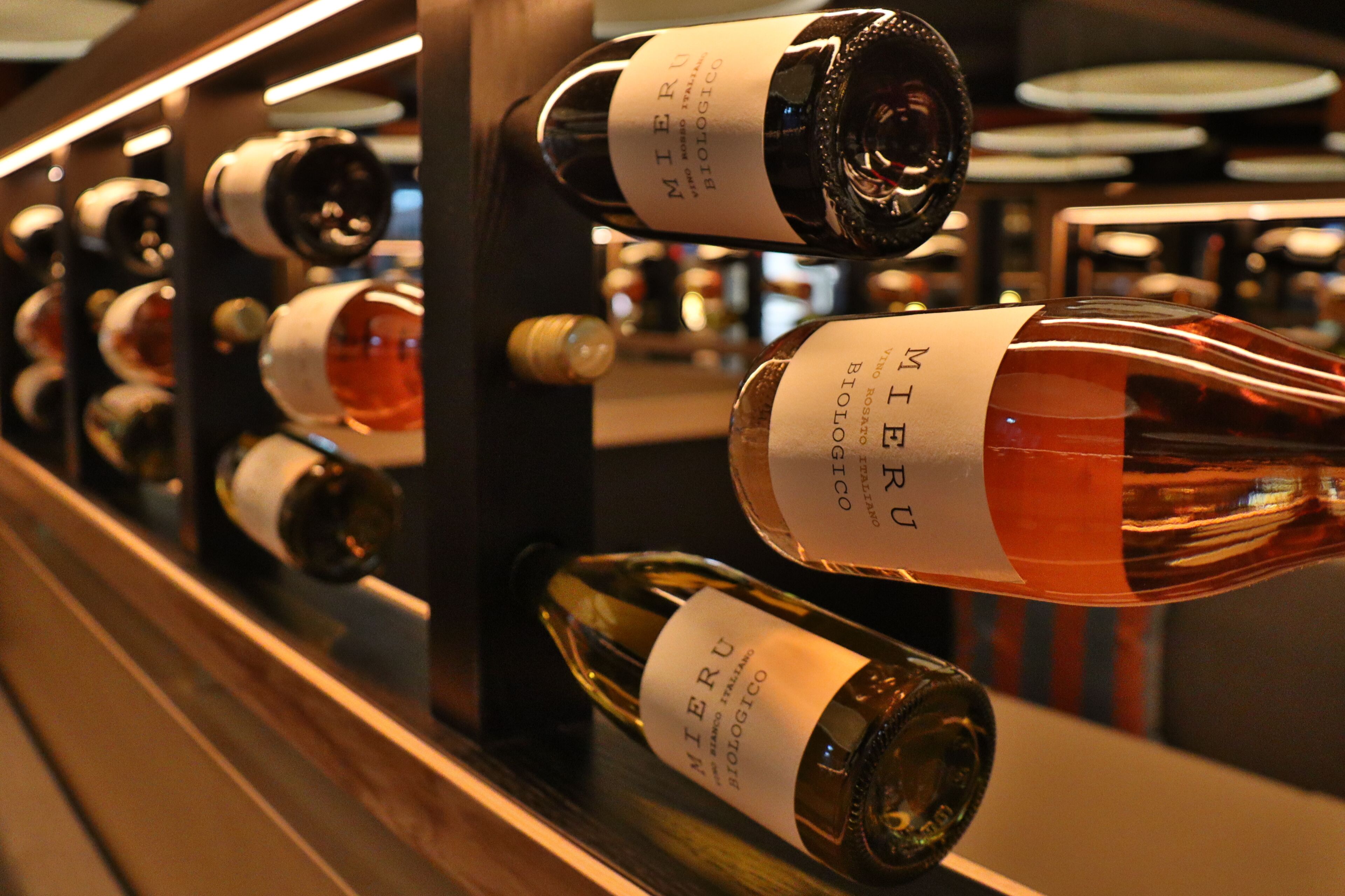 A wine rack with bottles labeled 'MIEU BIOLOGICO'.