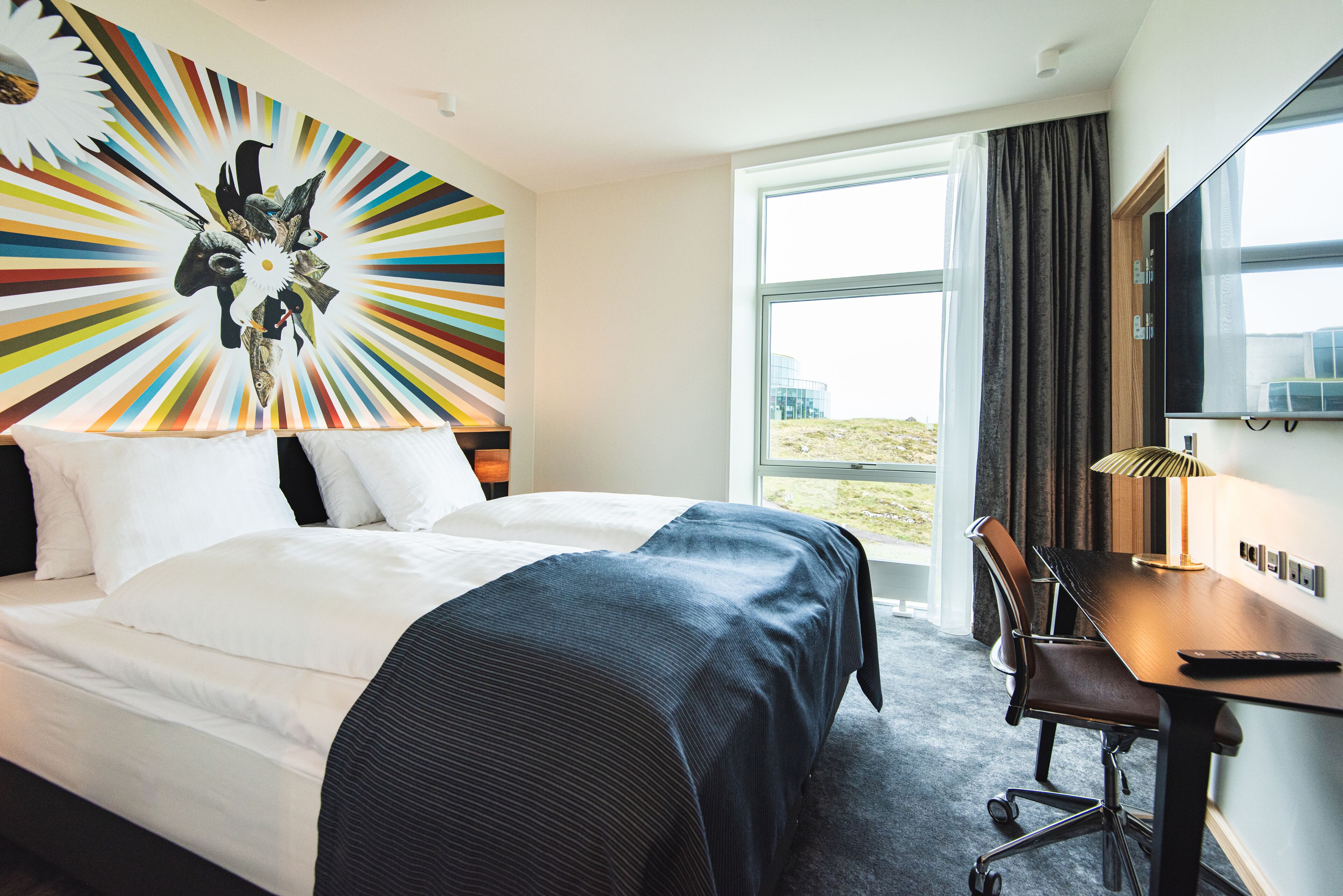 A hotel room with a large bed, a desk, and a view of the outdoors.