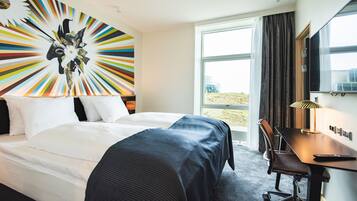 Een hotelkamer met een groot bed, een bureau en uitzicht op het landschap.