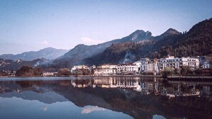 A lakeside town with buildings reflecting on the water, surrounded by mountains. - Greenland Sa Pa Hotel by DLMH (Sa Pa)