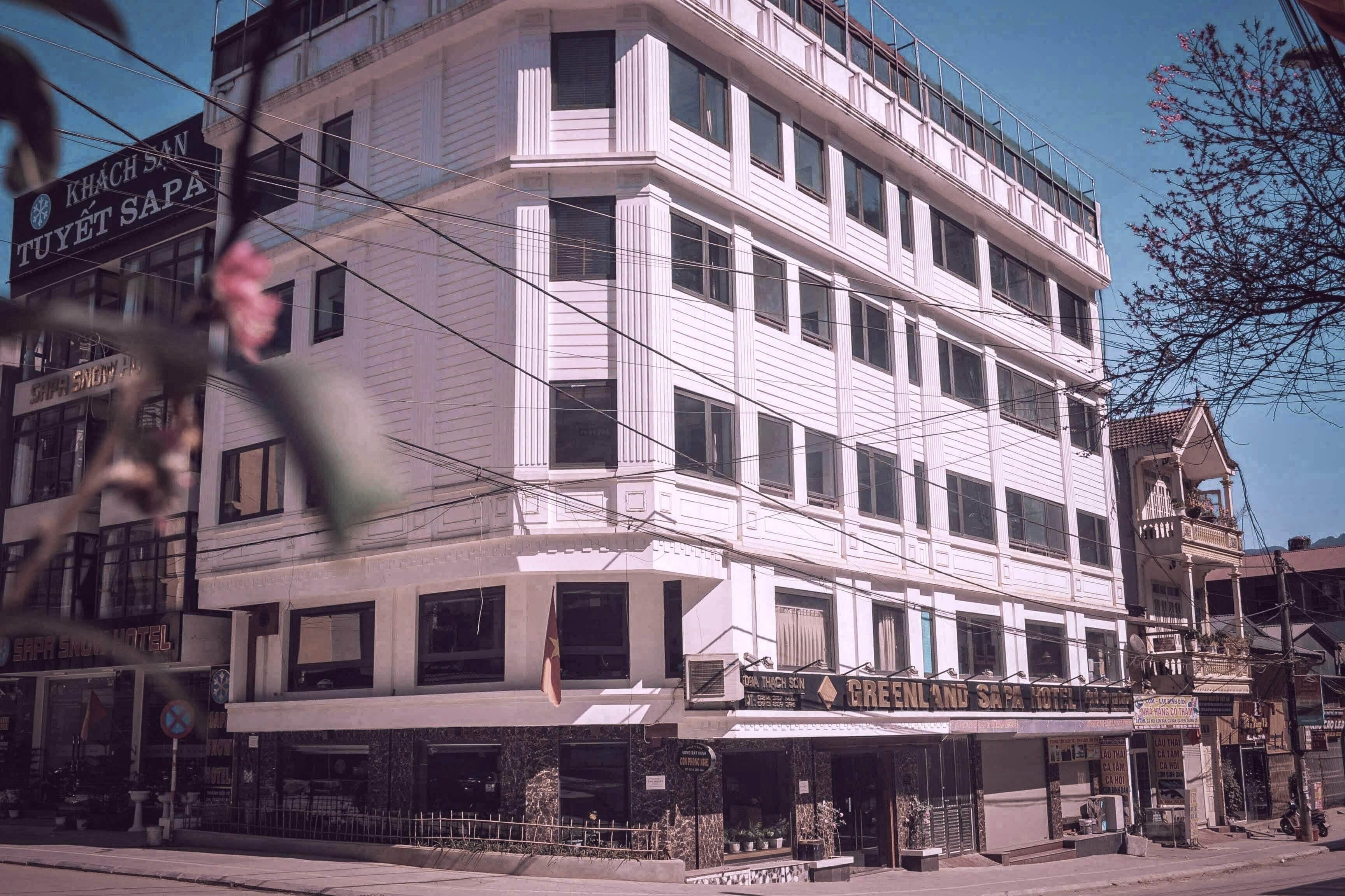Un hotel de varios pisos con un diseño arquitectónico clásico, que cuenta con un restaurante en la planta baja y una señalización visible del hotel.