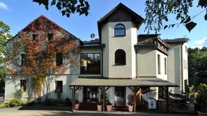 A two-story house with a covered patio area, a large window, and a satellite dish. - Obere Mühle (Bad Elster)