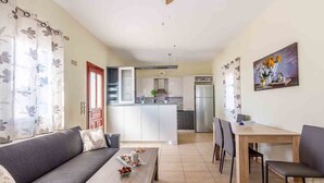 A modern living room with a sofa, coffee table, and dining area. - Spacious 2 Bedroom House with Fantastic Yard (Sifnos)
