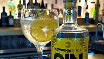 A bottle of Snowdonia Spirit Co. Jin Cymreig Lemon Gin and a glass with a lemon slice.