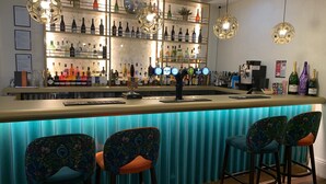Eine Bar mit einer Theke, mehreren Flaschenregalen und drei gestreiften Stühlen.