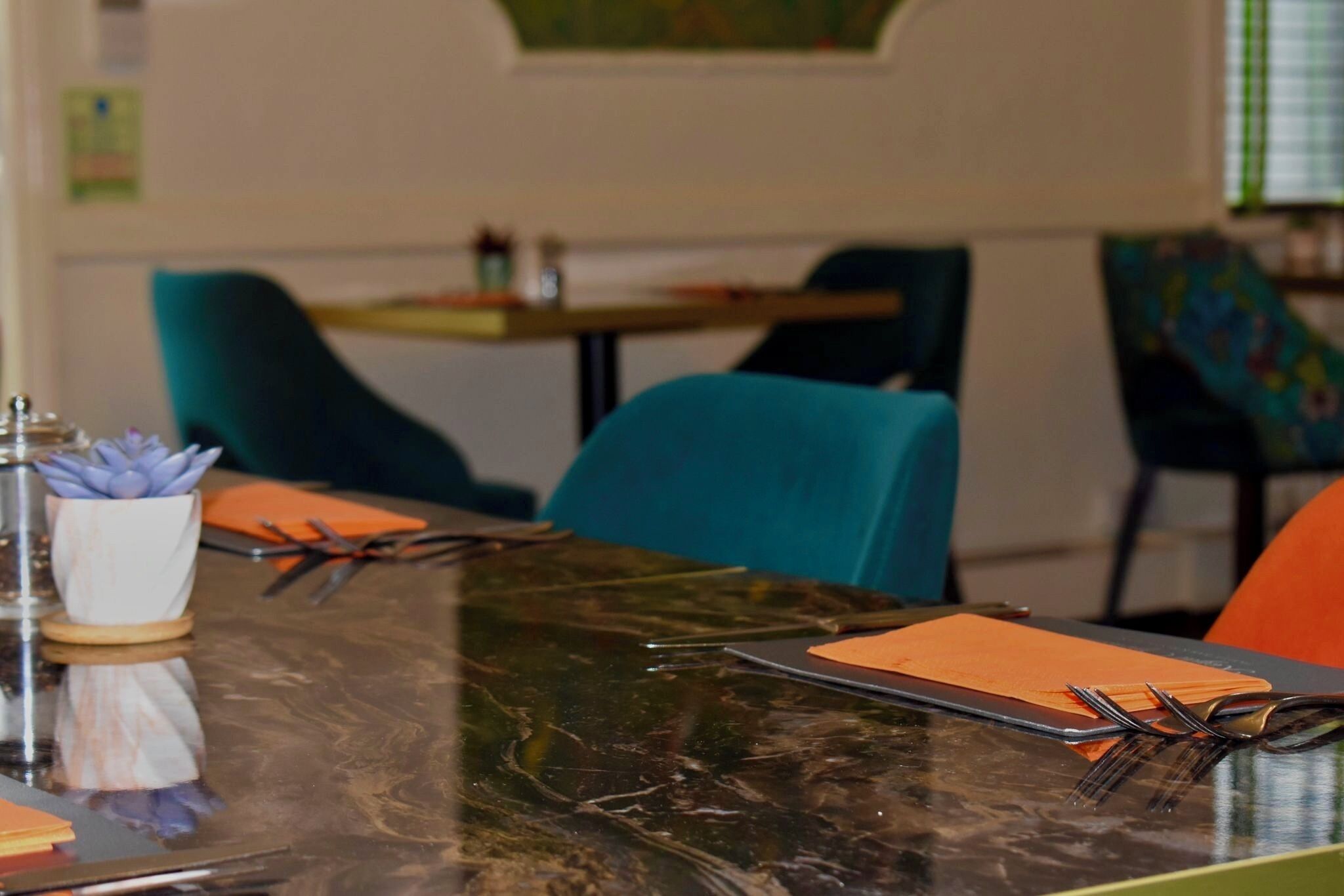 A dining table with a reflective surface, a pair of scissors, and a small potted plant.