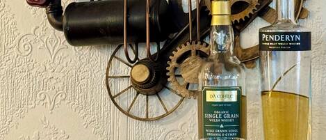 A wall clock, a barometer, and two bottles of whiskey on a shelf.