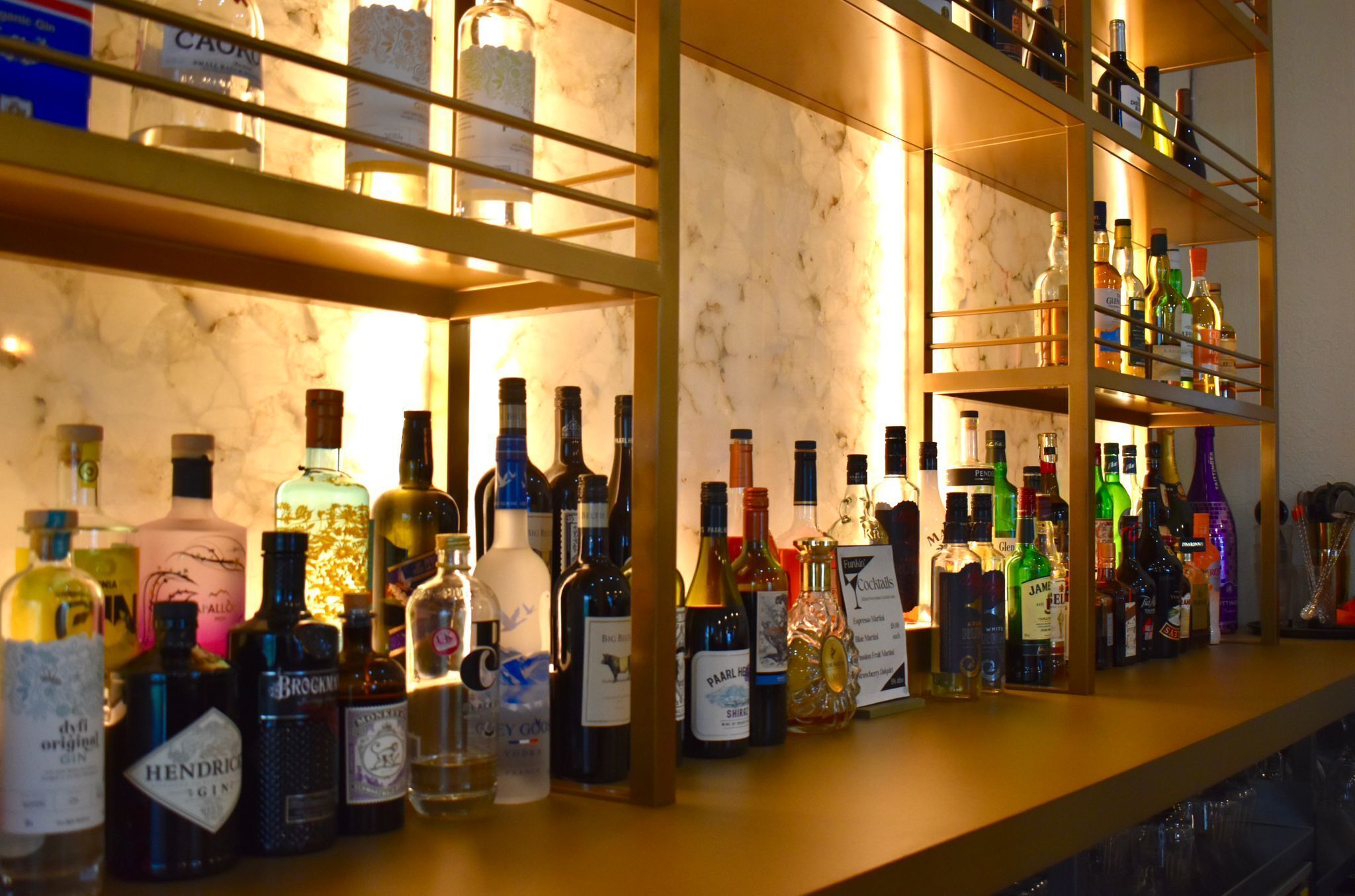 A bar area with shelves of various liquor bottles.