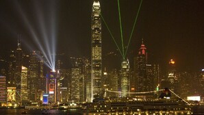 A cruise ship docked at a port with a city skyline in the background. - Rich Hostel (Kowloon)