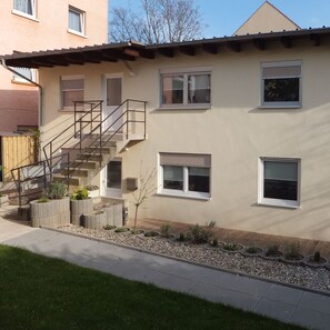 A two-story building with a staircase, multiple windows, and a small garden area with plants and gravel. - Monteurhaus Neumann (Mannheim)