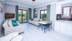 Una sala de estar moderna con sofá, mesa de comedor y zona de cocina.