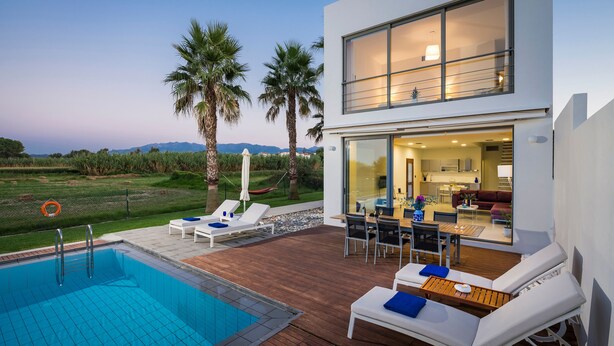 A modern house with a swimming pool, outdoor seating, and a view of the landscape.