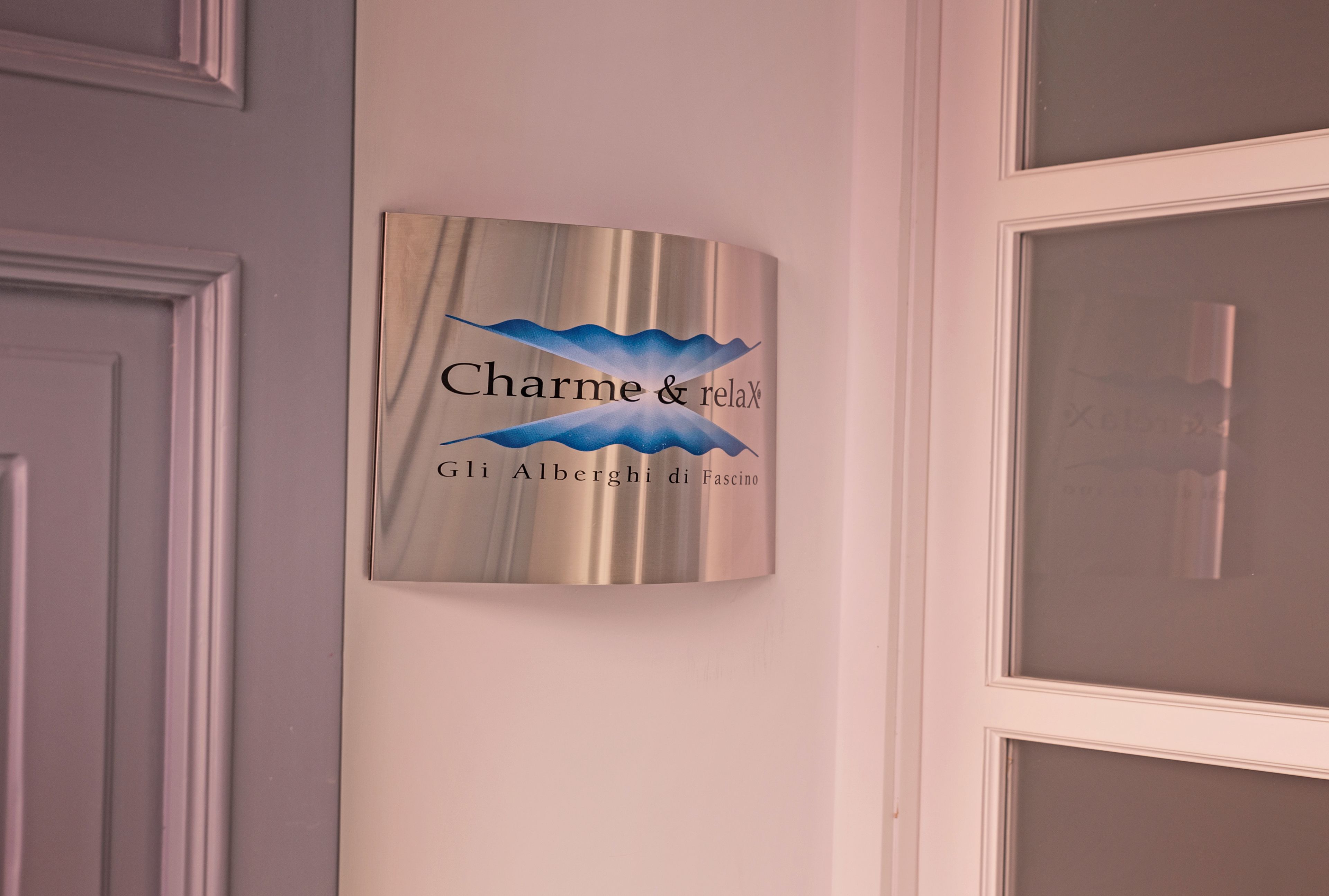 A wall-mounted sign with the text "Charme & relax Gli Alberghi di Fascino".