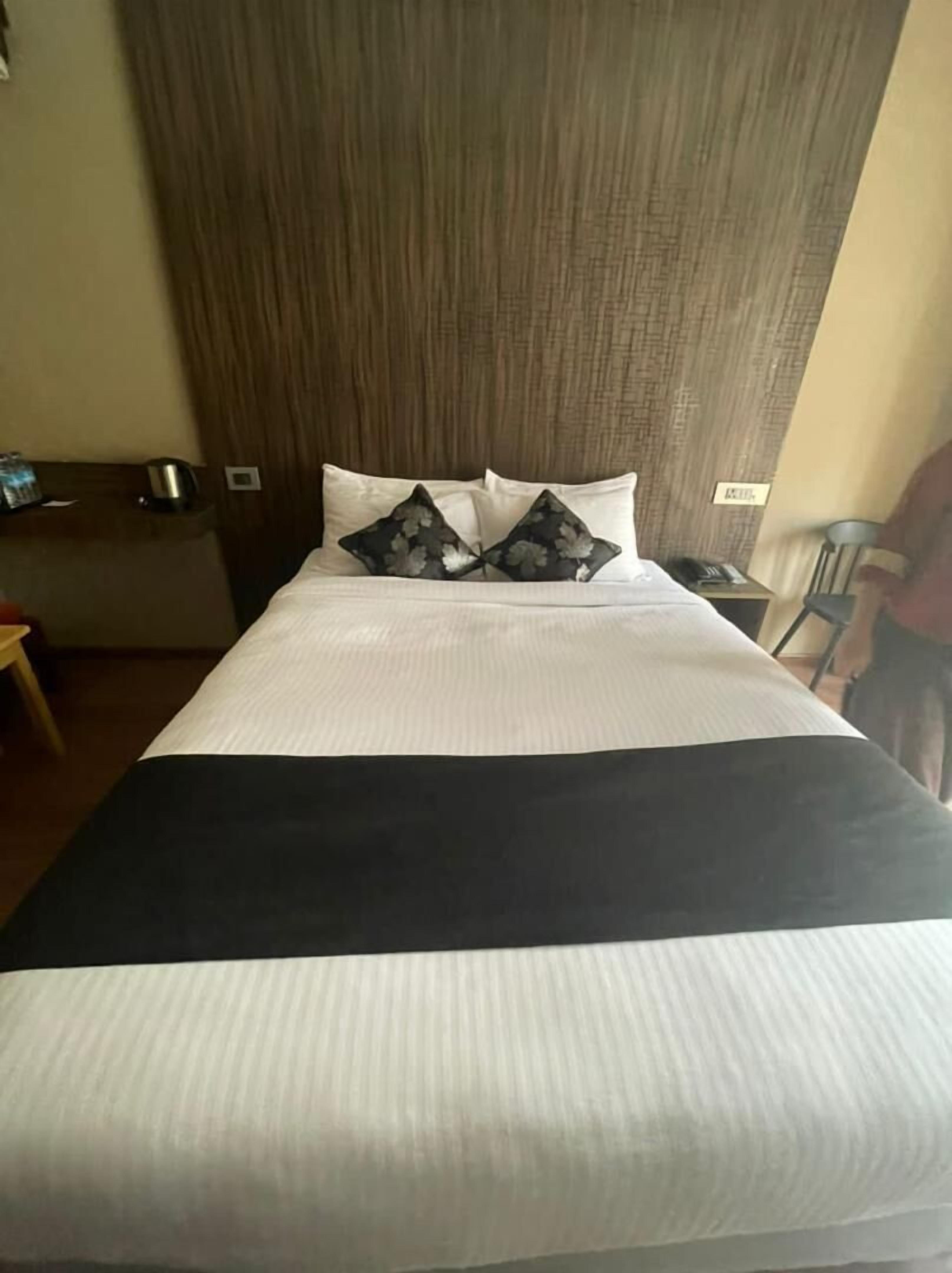 A hotel room with a bed, a headboard, a nightstand, and a chair.