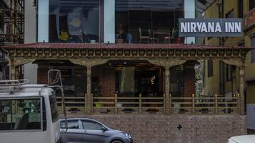Un bâtiment sur lequel on peut lire l’inscription « NIRVANA INN », de style architectural traditionnel, avec des balcons richement décorés et un toit recouvert de tuiles.