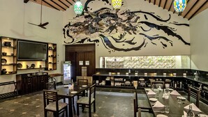 A restaurant with a long dining table, chairs, and a bar area.