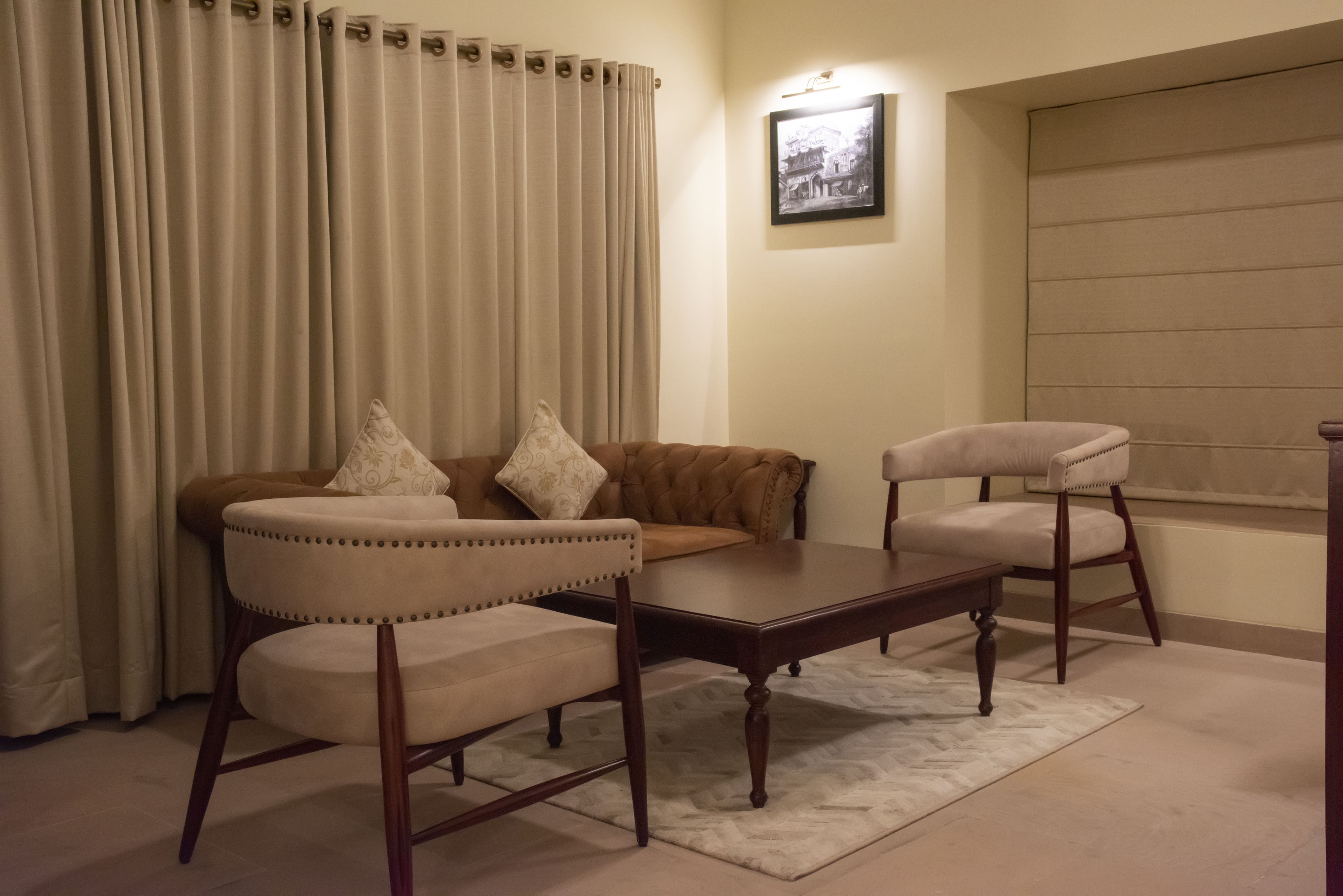 A living room with a brown sofa, two armchairs, a wooden coffee table, and a patterned rug.