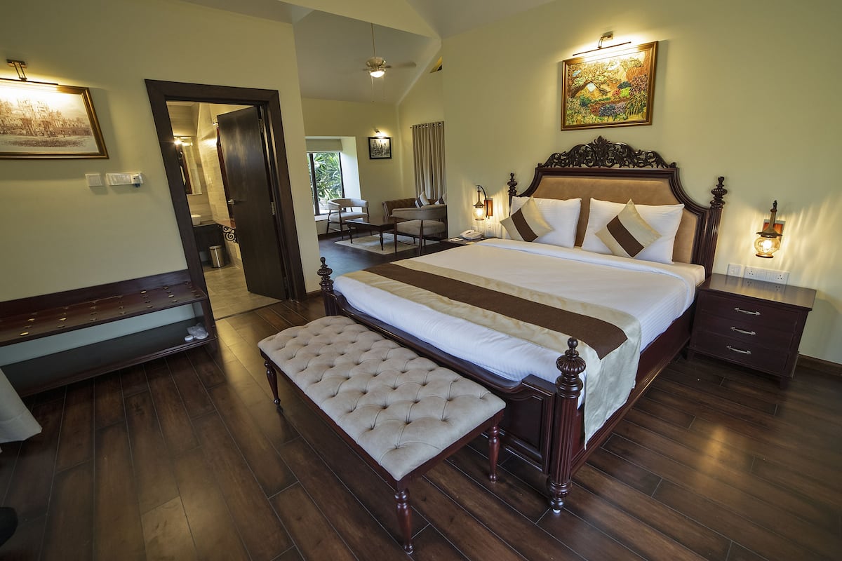 A spacious bedroom with a large bed, a bench, a nightstand, and a desk.