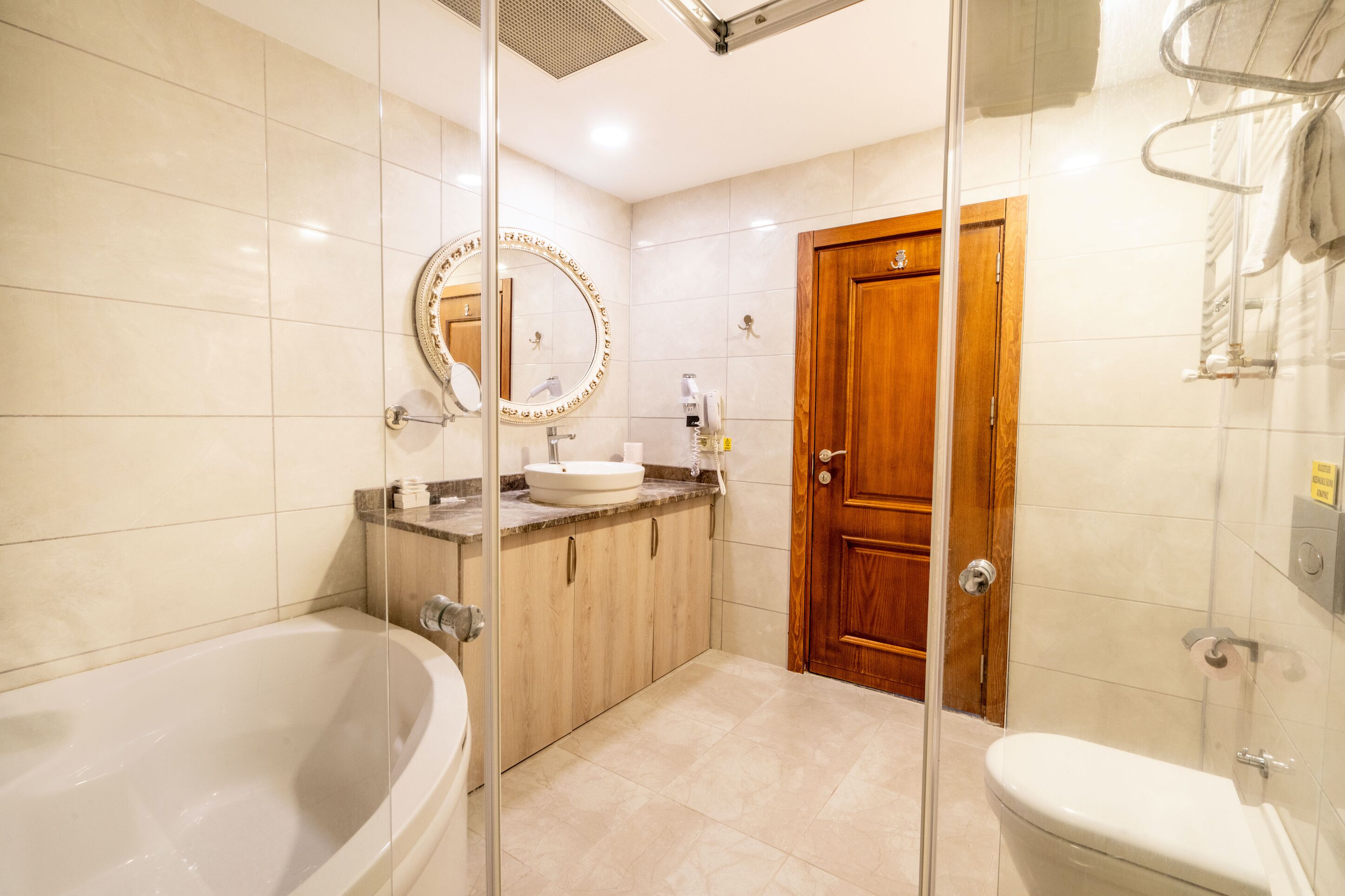 Un baño con bañera, lavamanos, inodoro y puerta de madera.