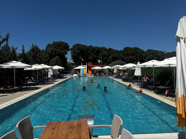 Una piscina al aire libre de temporada, sombrillas, tumbonas