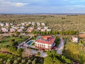 A residential area with multiple white buildings, a swimming pool, and green surroundings. - Helen Troya Hotel Geyikli (Ezine)