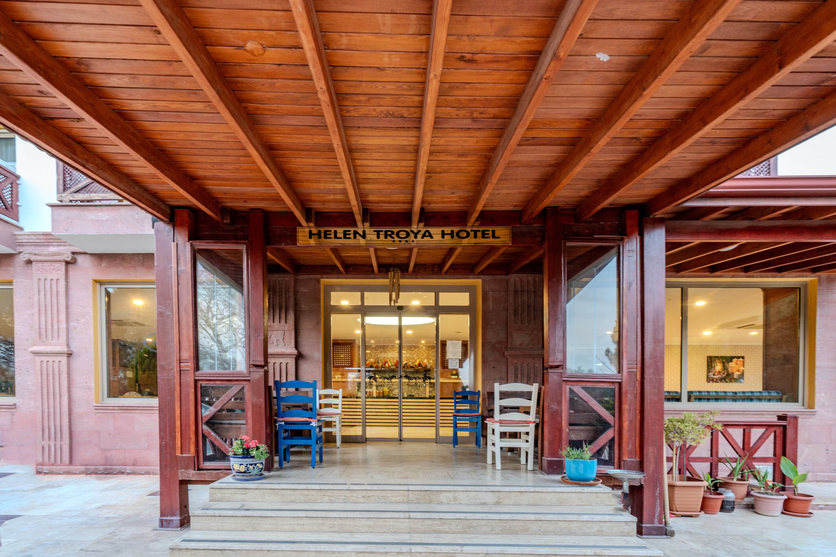L'entrée de l'hôtel Helen Troya, avec sa façade en bois, sa porte en verre et une enseigne au-dessus de l'entrée.