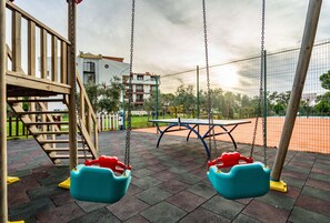 A playground with swings, a slide, and a tennis court. - Helen Troya Hotel Geyikli (Ezine)