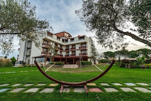A multi-story building with balconies, a central courtyard, and a hammock. - Helen Troya Hotel Geyikli (Ezine)