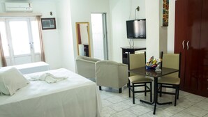 Una habitación de hotel con cama, escritorio con silla, televisor y armario.