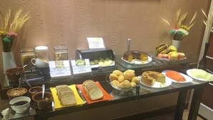 Un bufé con distintos alimentos, como pan, bollería y frutas.
