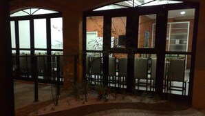 Un área de recepción con disposición de asientos, un pequeño jardín y vistas a través de grandes puertas de vidrio.