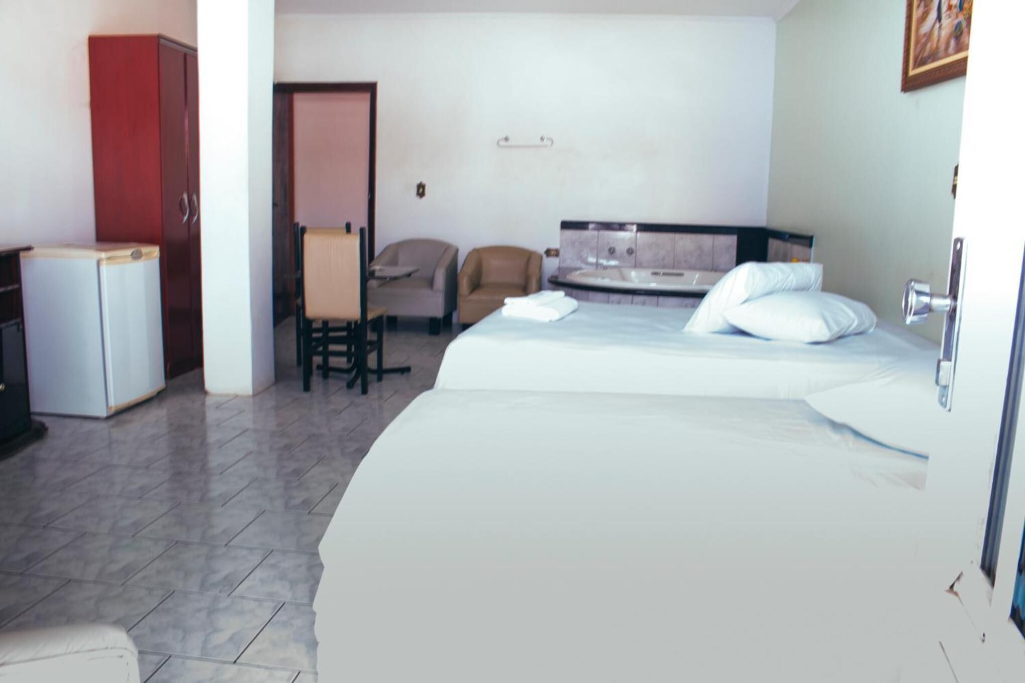 Een hotelkamer met een bed, een bureau, een stoel, een kledingkast en een kleine koelkast.