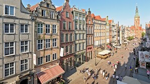 Ett historiskt europeiskt torg med traditionell arkitektur, kullerstensgator och ett framträdande klocktorn.