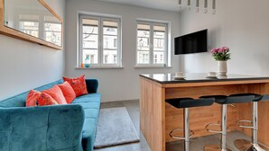 Ett modernt vardagsrum med en blå soffa, ett träbord och en tv som är monterad på väggen.