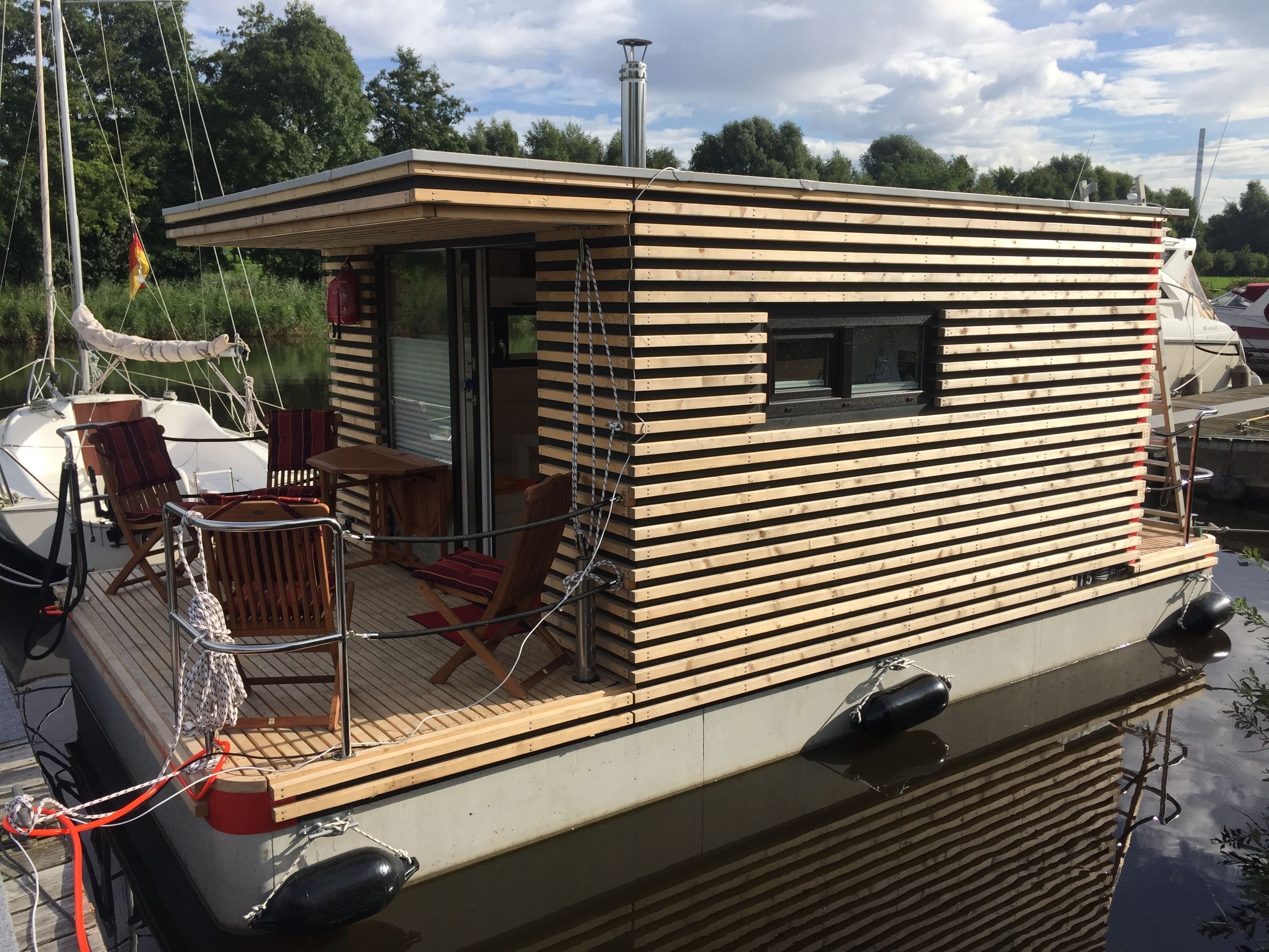 Une petite cabane en bois avec une terrasse, une table et des chaises.