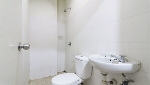 A small, clean bathroom with a toilet, sink, and shower. - Anno Guesthouse (Makassar)