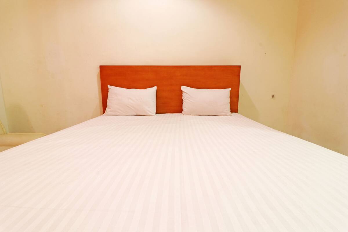 A neatly made bed with a wooden headboard and two pillows.